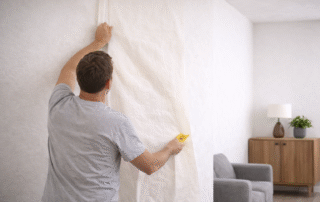 Man behangt glasvlies behang op stucwerk.