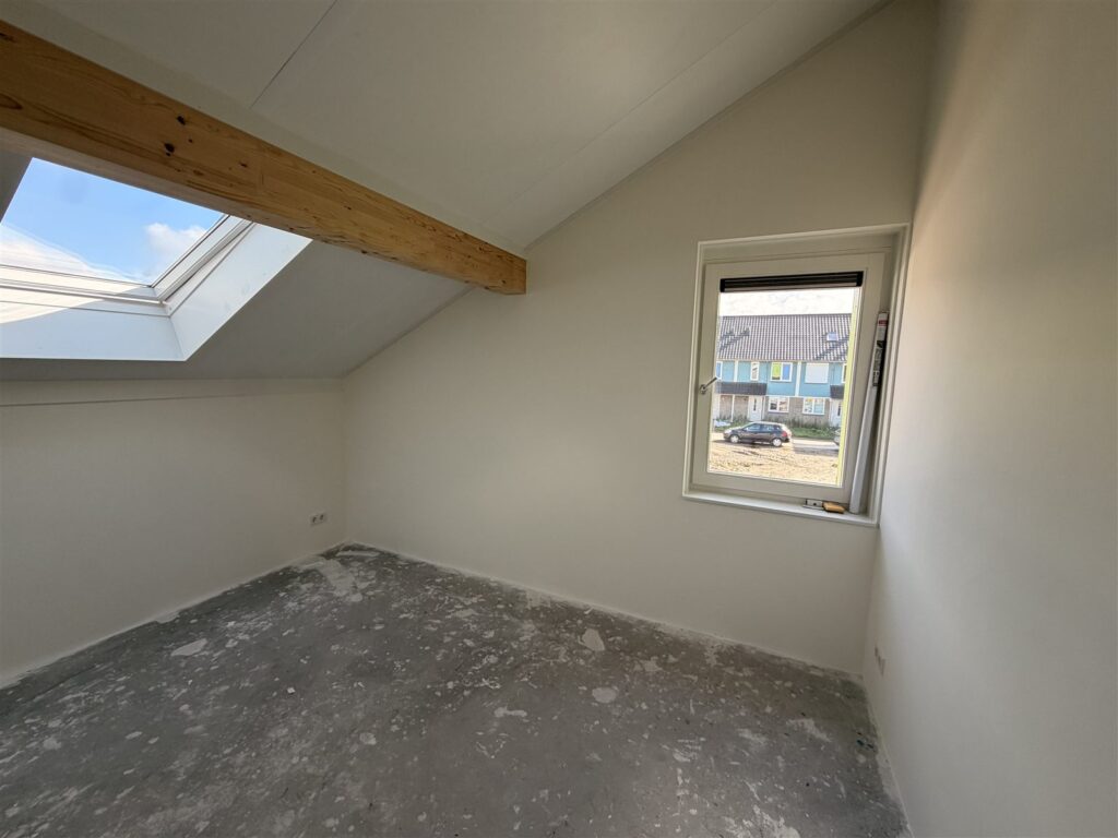 Kamer onder een schuin dak met dakraam en witte wanden