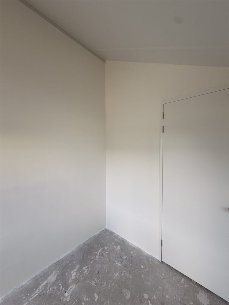 Smalle ruimte met strakke witte wanden en een binnendeur