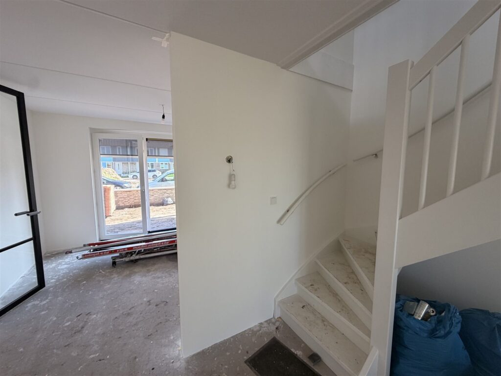 Hal met trap en gladde witte wanden in een nieuwbouwwoning
