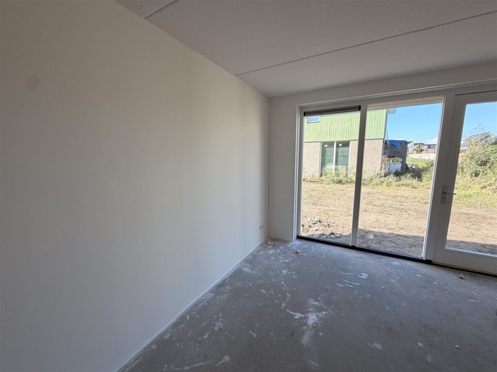 Lege nieuwbouwwoonkamer met gladde witte wanden en tuindeuren
