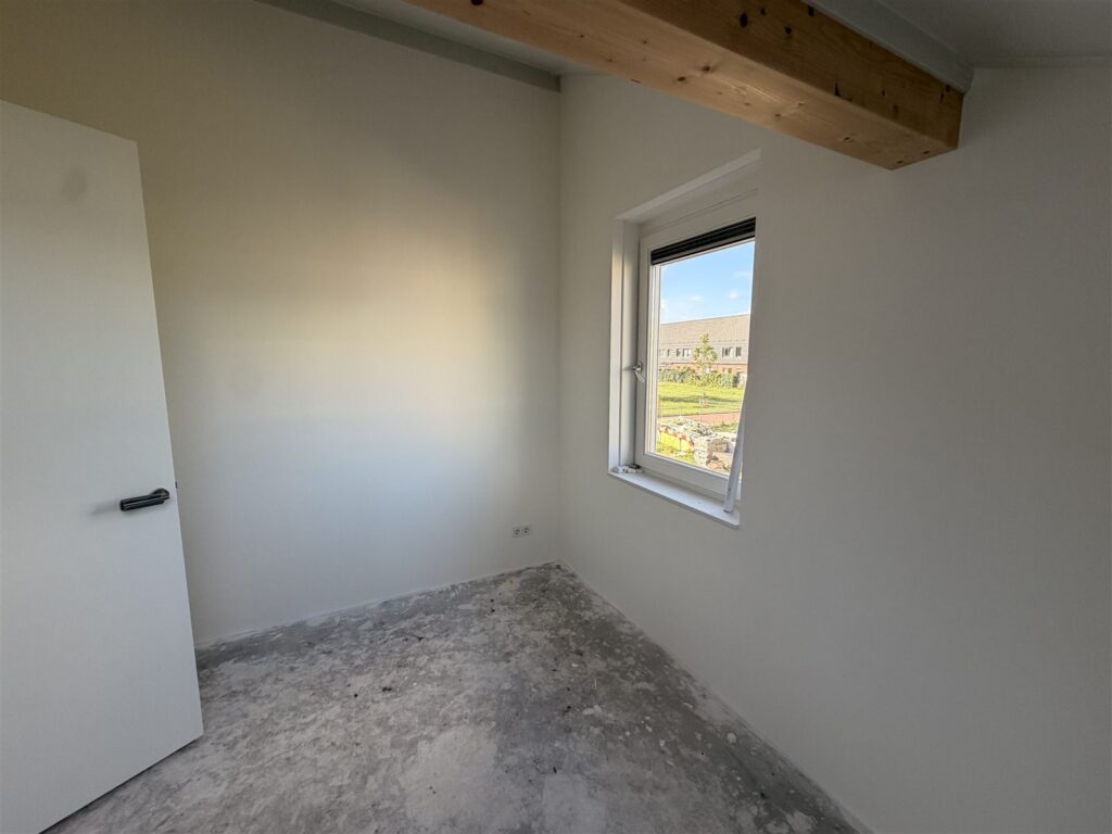 Slaapkamer met strakke witte wanden en een raam