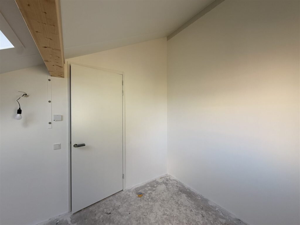 Slaapkamer onder een schuin dak met egale witte wanden