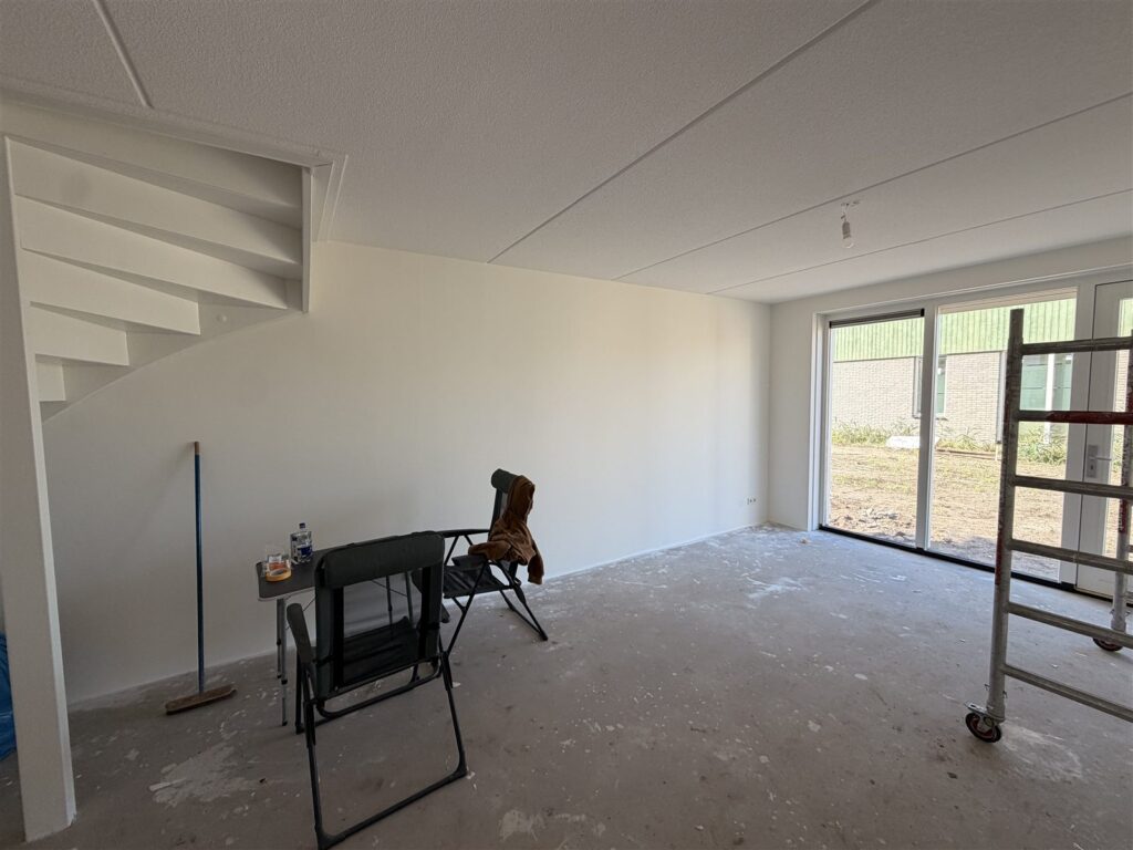 Woonkamer met trap en gesausde wanden, klaar voor de verhuizing